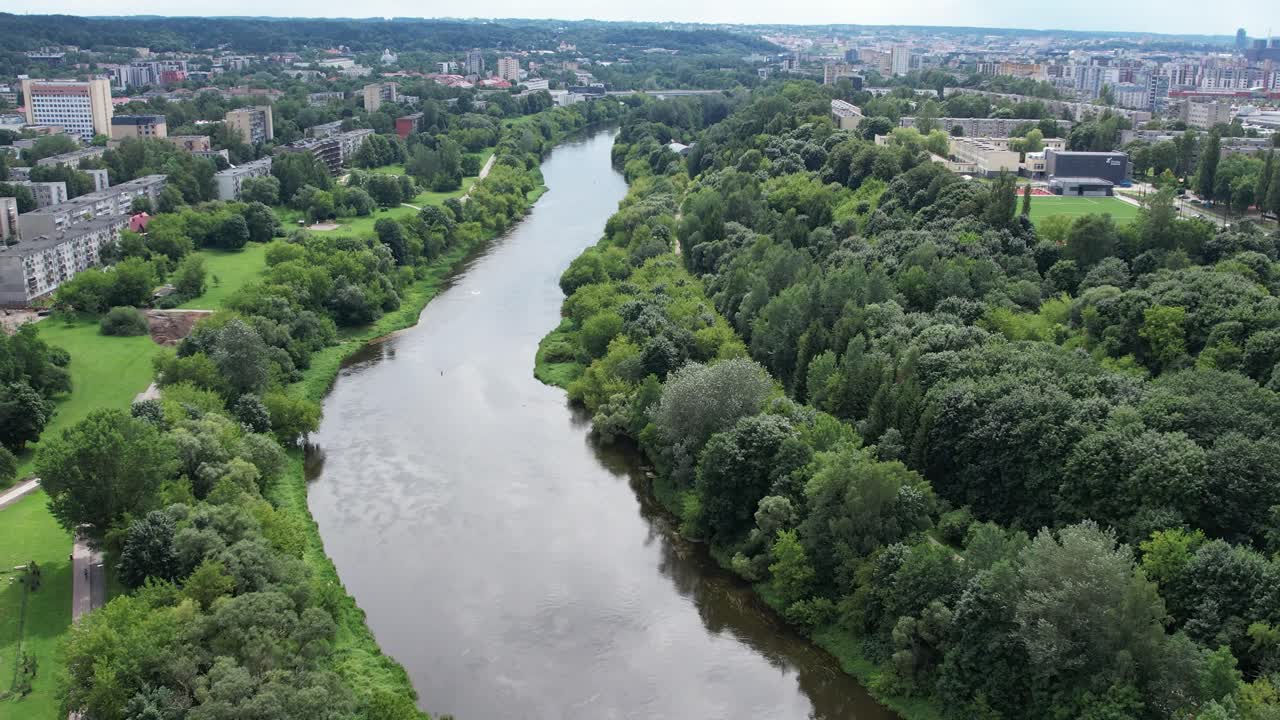 Luftfoto over Neris-floden i Vilnius, der viser frodige, grønne bredder, boligkvarterer og fredfyldte sommerlandskaber, der strækker sig gennem byen