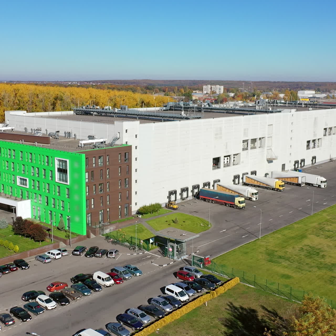 Aerial view of a modern plant. Huge factory and parking place with cars outdoors. Contemporary industrial complex in the city. Camera moves up.