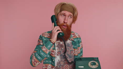 Hippie-redhead-man-talking-on-wired-vintage-telephone-of-80s,-says-hey-you-call-me-back-conversation