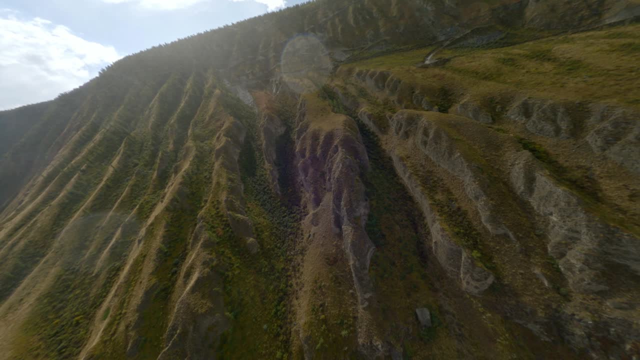 Upward flight over mountain serpentine sharp turns road with rain drops through sun lights glare