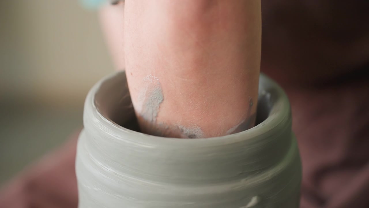Concentrandosi sulla modellazione a mano di un cilindro in ceramica. L'argilla viene modellata con cura a mano su un tornio. L'artigiano centra con perizia l'argilla umida sul tornio rotante con pressione precisa.
