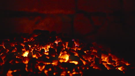 Fiery-coals-in-dark-stove,-nighttime-heat-source-close-up