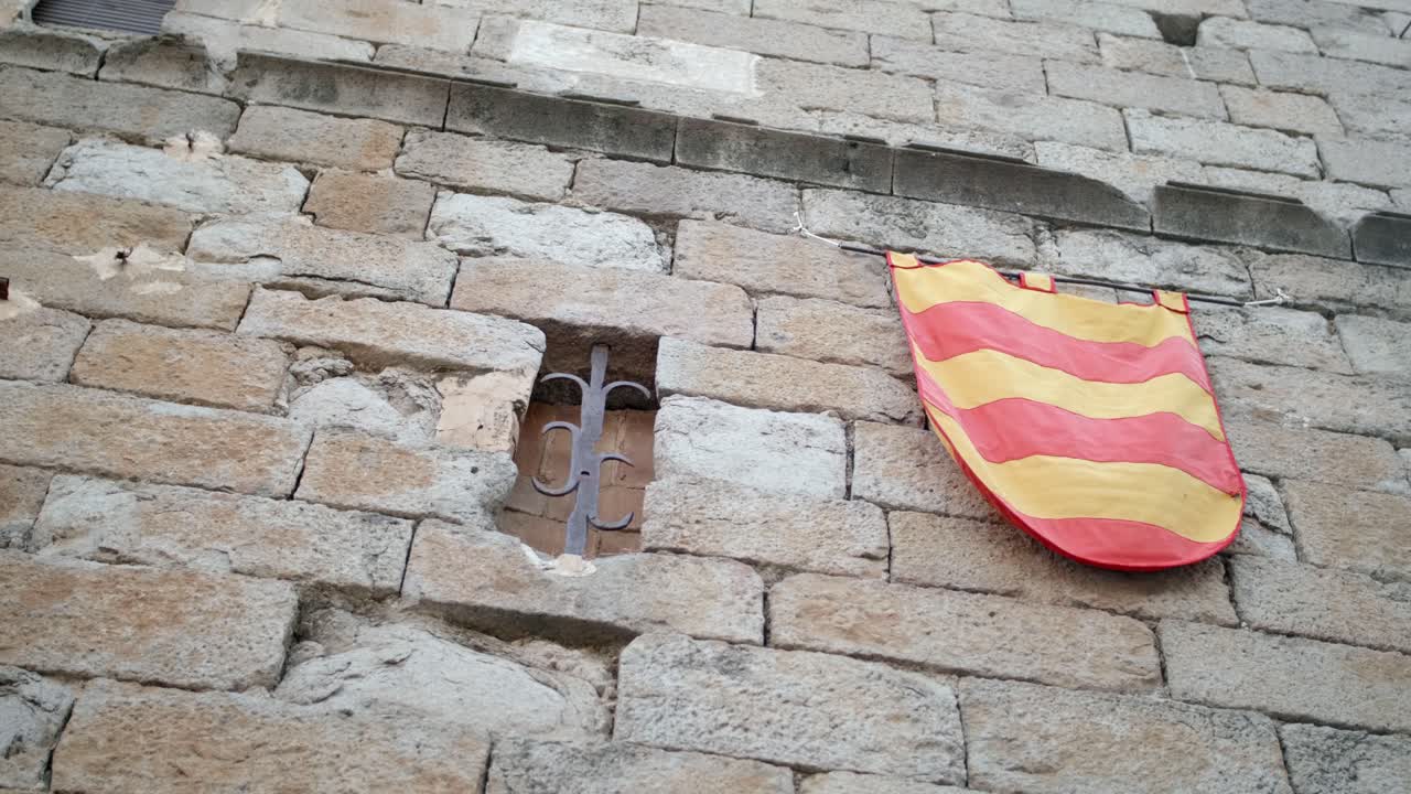 la senyera, bandera de cataluña, colgada en la pared exterior de un edificio medieval en españa