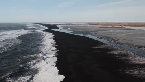 black sandy beach with reaching waves at sunset
