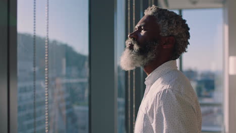 mature african american businessman looking out window planning ahead thinking of ideas for future business development with view of city at sunset 4k