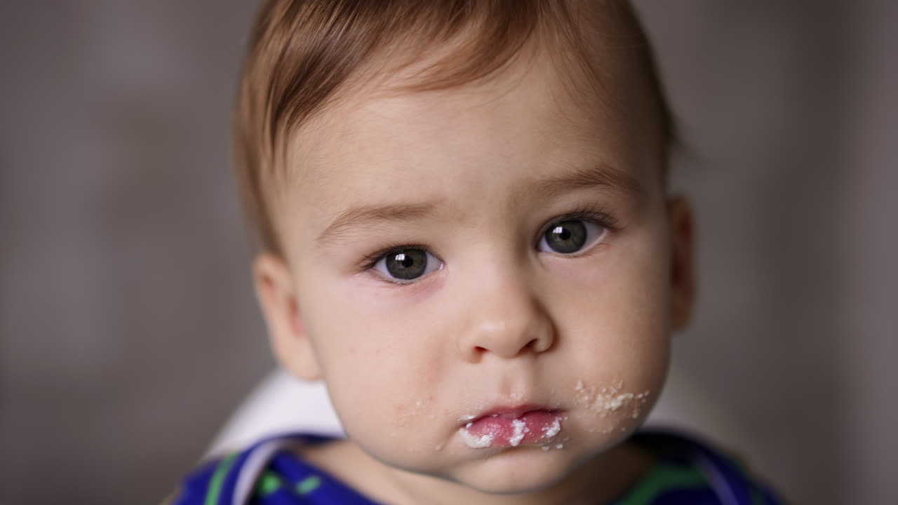 Sweet adorable baby face during having meals. Portrait of an adorable Caucasian kid with smudged face. Close up.