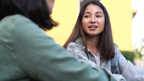 dos chicas japonesas muy jóvenes sentadas y hablando juntas al aire libre 2