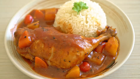 homemade chicken stew with tomatoes, onions, carrot and potatoes on plate with rice