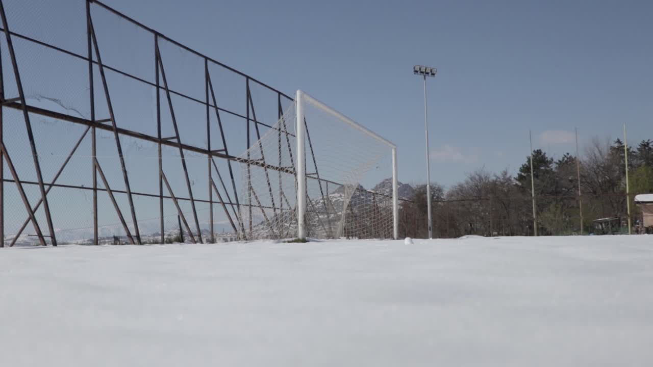 Football field covered in snow and an empty football goal in winter.