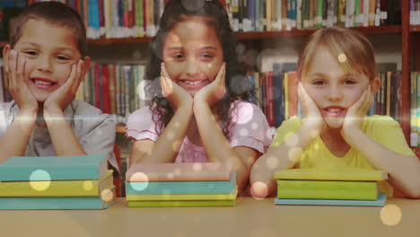 escolares apoyadas en una mesa y mirando a la cámara con libros delante de ellos en una biblioteca