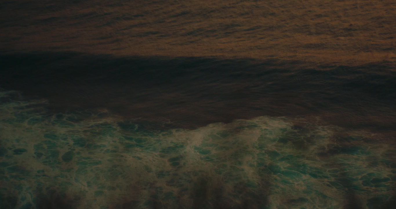 Close-up of turquoise ocean waves and white foam washing over a golden sandy beach. Peaceful tropical shoreline atmosphere for travel and vacation themes