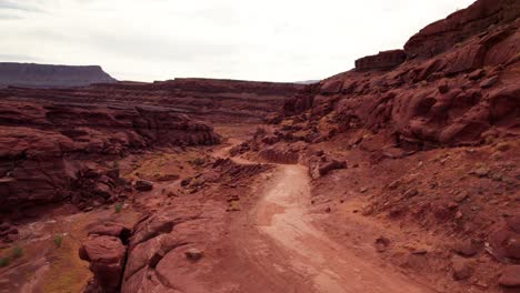 Drone-shot-flying-down-an-off-road-trail-in-Moab,-Utah-in-the-fall