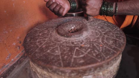 indian woman pours dal into a handgrinder