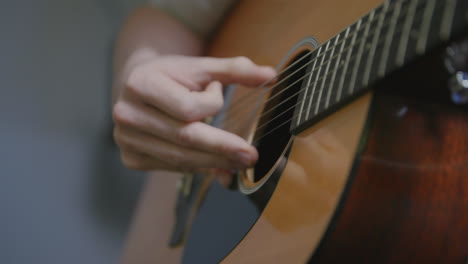 imágenes de primer plano en cámara lenta de los dedos de un hombre tocando y rasgueando una guitarra acústica