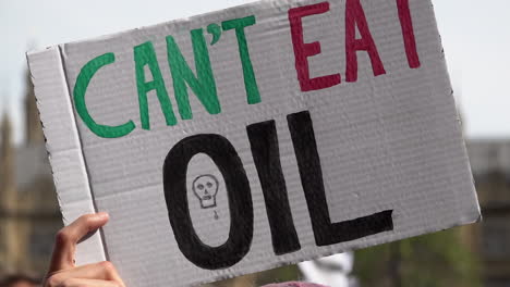 a handmade placard is held up that reads “can’t eat oil” on an extinction rebellion protest calling for an end to fossil fuel dependency