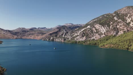 Boats-anchored-in-beautiful-deep-blue-waters-at-base-of-stunning-Green-Canyon,-Taurus-mountains-Turkey