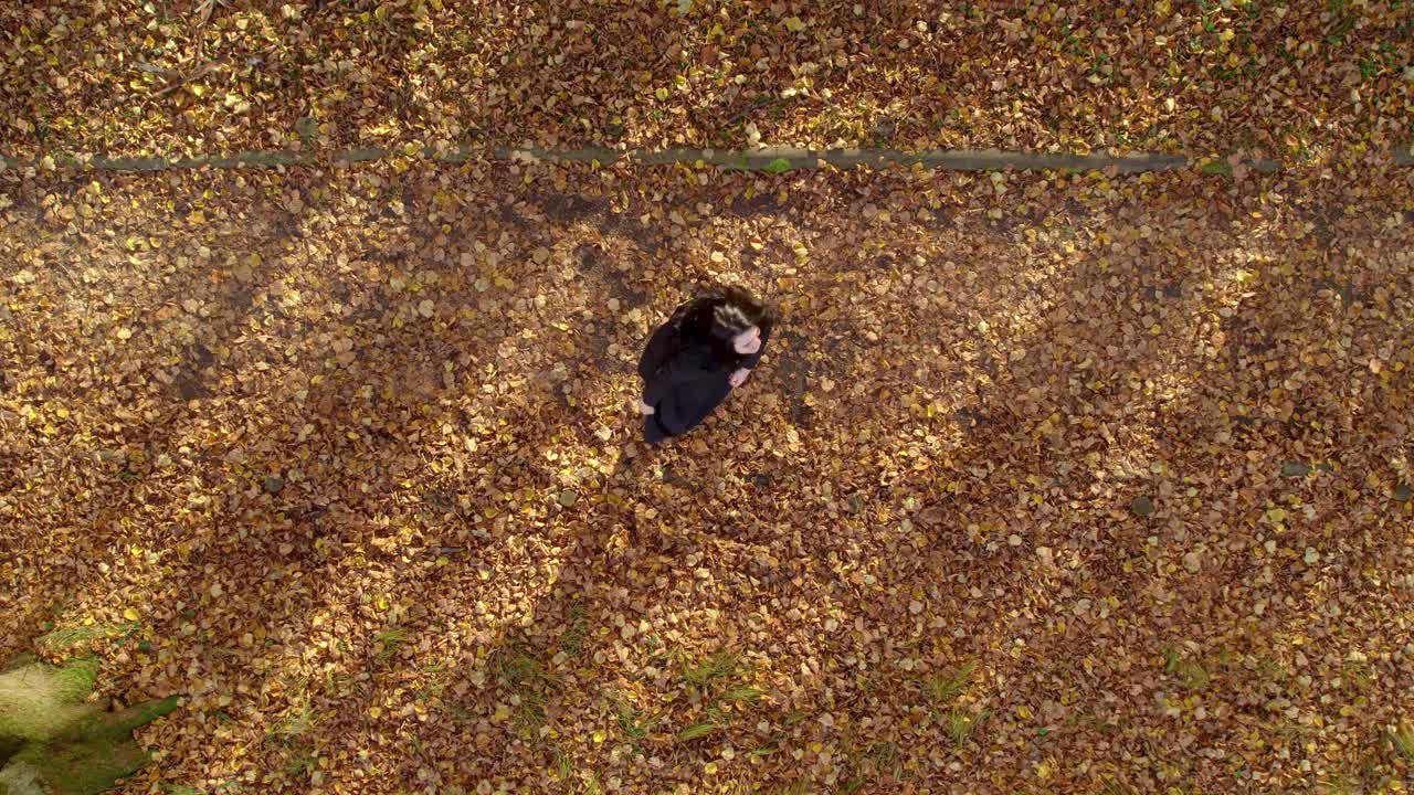 검은 드레스를 입은 소녀가 화창한 가을날을 즐기고 있다.