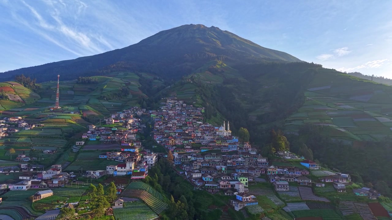 Ripresa drone di un villaggio montano rurale con campi terrazzati e paesaggio vulcanico. Scena di campagna pacifica con un'atmosfera naturale fresca e bellezza paesaggistica. Nepal Van Java, Indonesia.