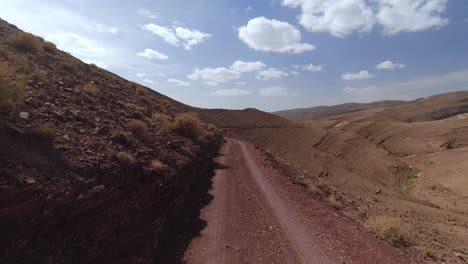 Point-of-view-of-a-driver-next-to-a-cliff-on-a-desert-mountain-dirt-road