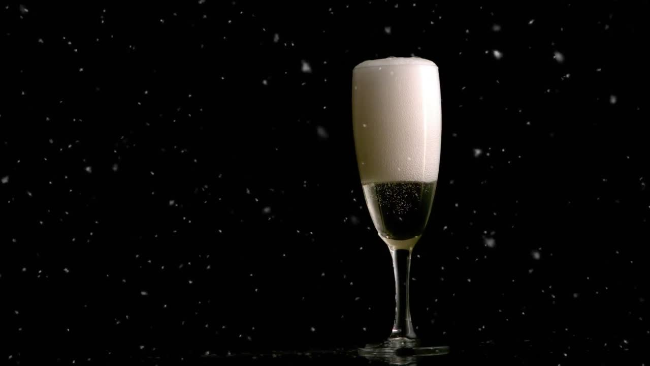 Animation von fallendem Schnee über einem Sektglas