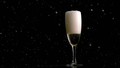 Animation-of-snow-falling-over-glass-of-champagne