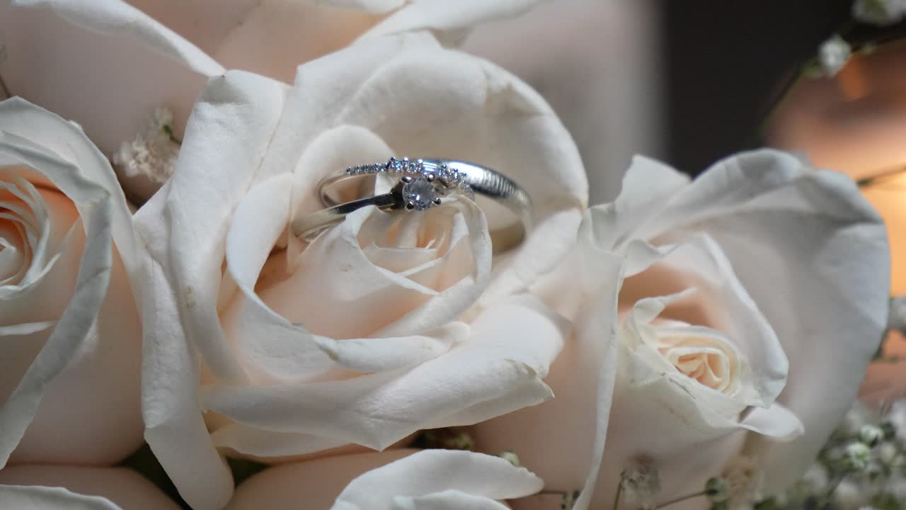 Shiny white gold wedding rings among the rose petals of the bride's bouquet