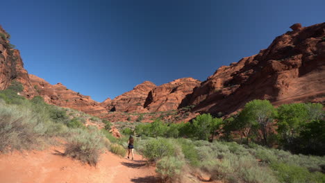 young lonesome woman walking on a desert trail under red rock sandstone hills in utah, st