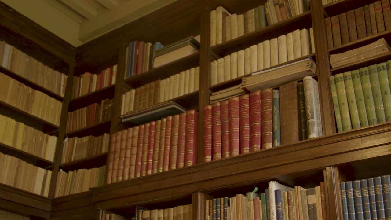 Panning over old books on high shelf in luxurious private library