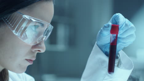 female scientist examining blood sample in test tube during medical test in lab