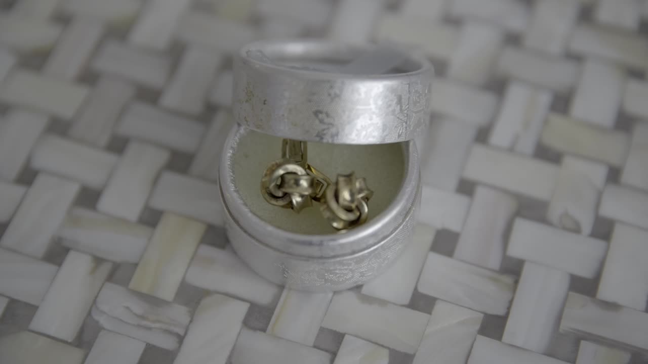 Close-up shot of a pair of cufflinks in an elegant silver box, showcasing luxury and detail.