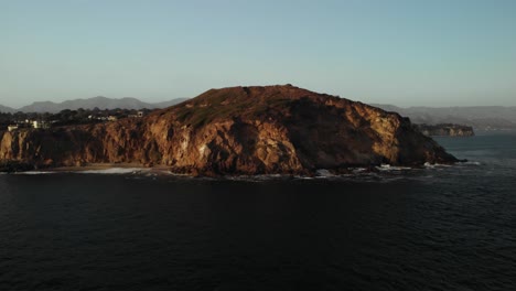 an aerial shot of the beautiful point dume cliff in malibu on a calm evening as the vibrant sunsets