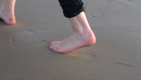 feet of a caucasian man walking barefoot at the sandy shoreline