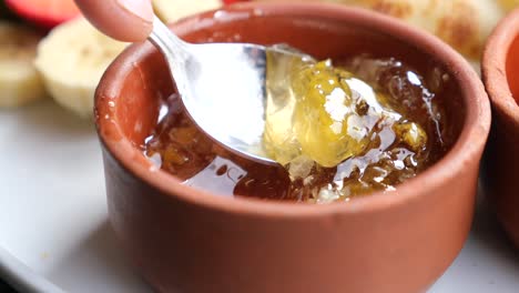 close up of golden honey being scooped out of a jar