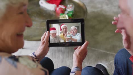 Pareja-Caucásica-Mayor-Usando-Tableta-Para-Videollamada-Navideña-Con-Familia-Feliz-En-La-Pantalla