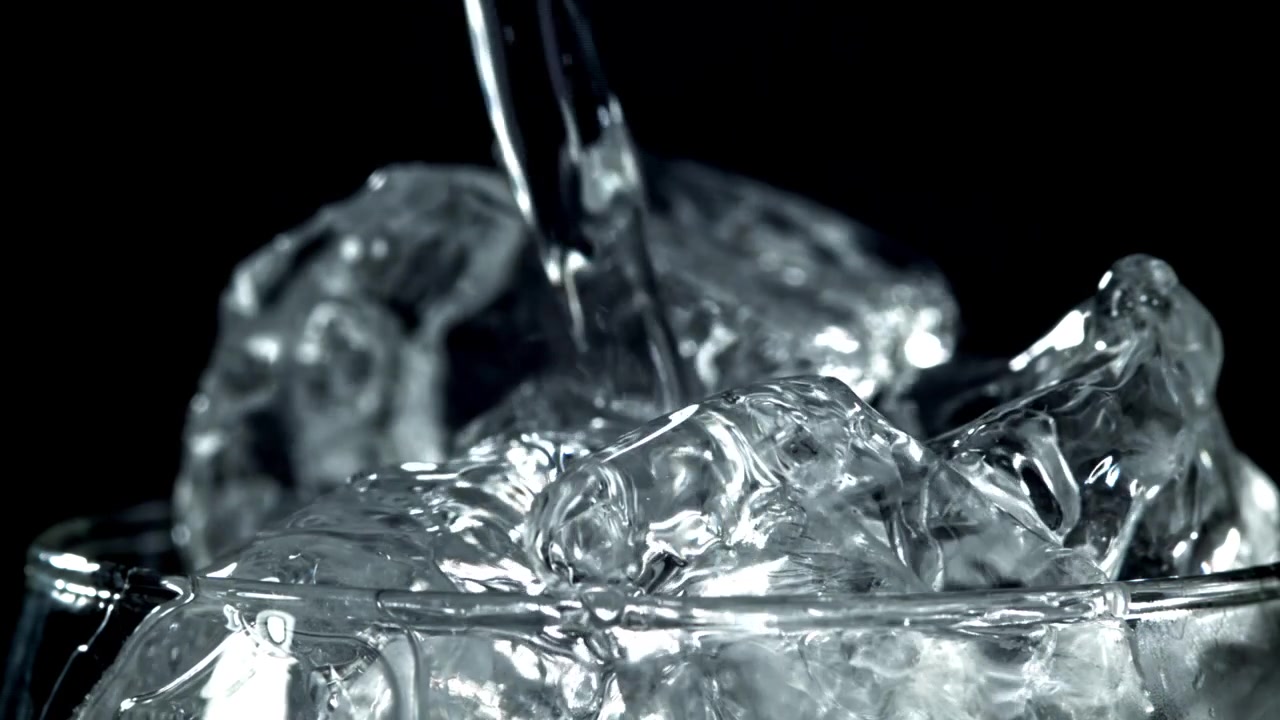 Acqua rinfrescante che si versa in un bicchiere di cubetti di ghiaccio