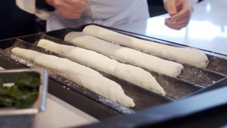 Chef-puts-the-bread-dough-into-black-baking-tray