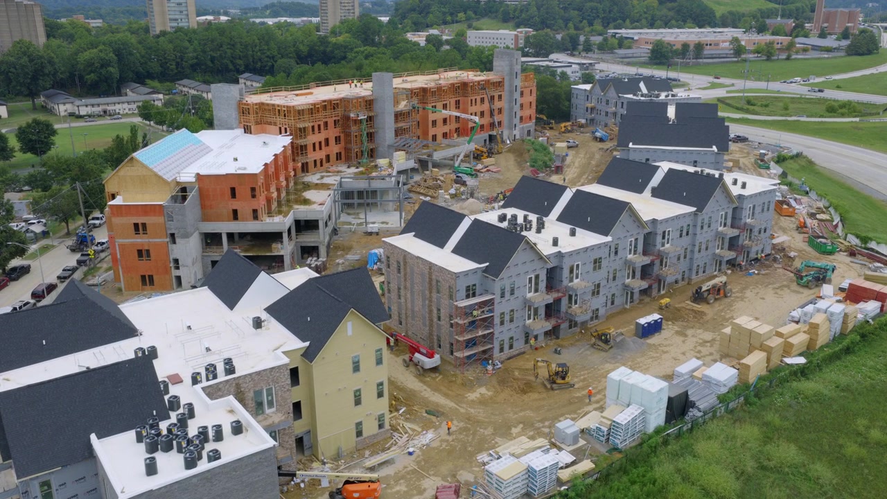 Aerial drone view of an apartment complex under construction in Chattanooga, Tennessee, with framed buildings and city towers in the background.