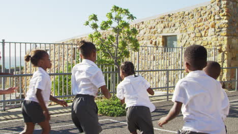 teacher passes football to young kids in school playground