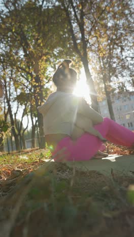 woman practicing yoga with her pug in a park