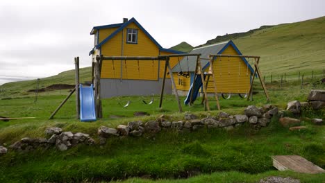 Wooden-swings-hanging-from-poles-swaying-on-a-breezy-day-on-Mykines,-Faroe-Islands