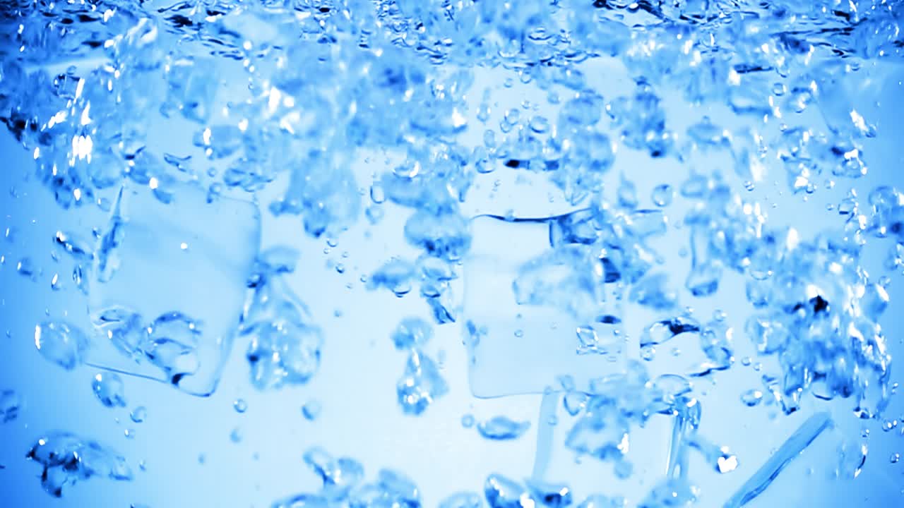 얼음 큐브가 공기 거품으로 물에 떨어집니다.