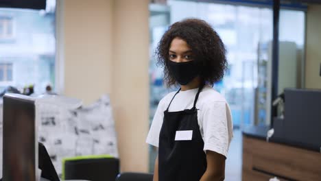 portrait of an african american worker at grocery store checkout, wearing mask