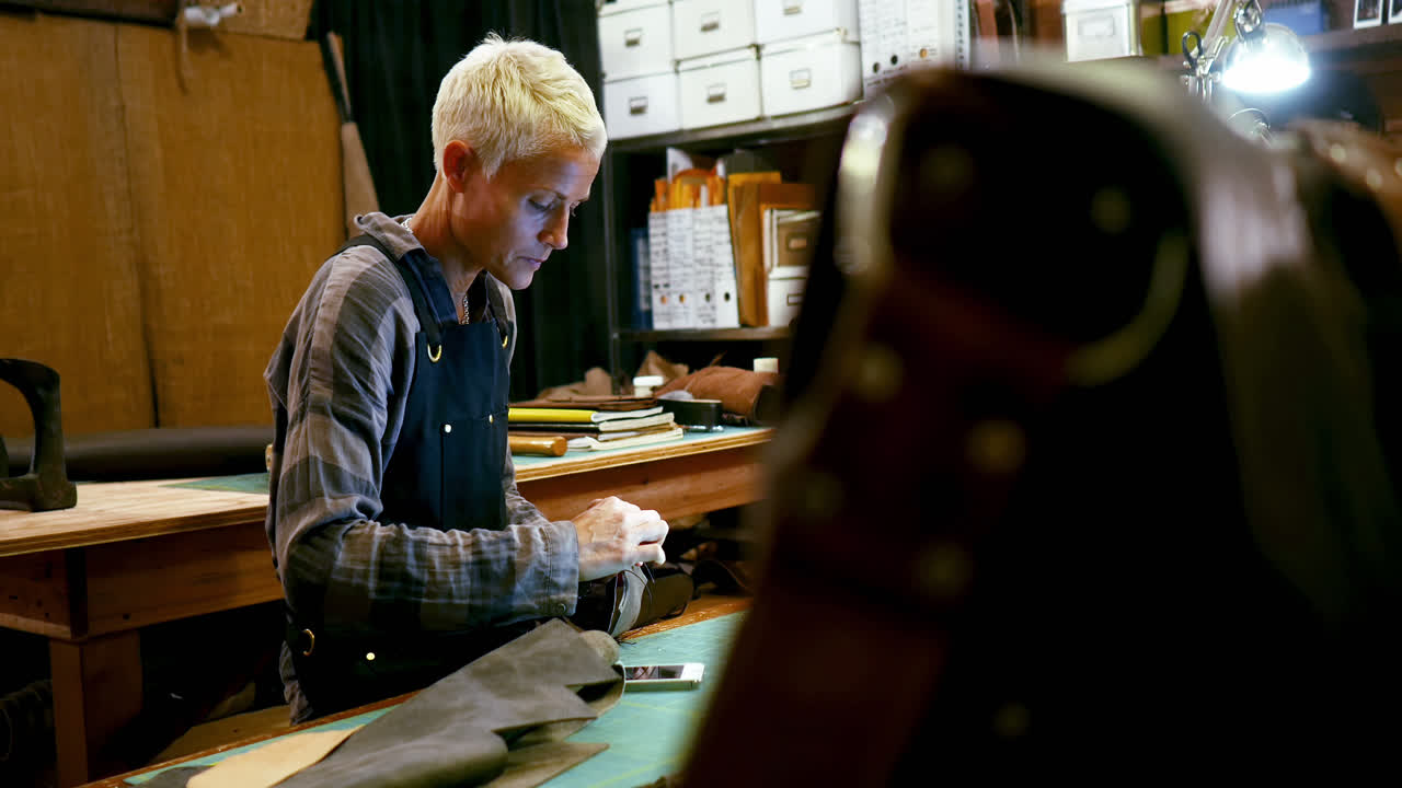 una artesana cosiendo un pedazo de cuero