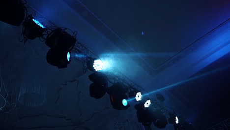 colorful spotlights on the dark background. different projectors spinning and glowing with laser rays inside the dance club. led lighting equipment.