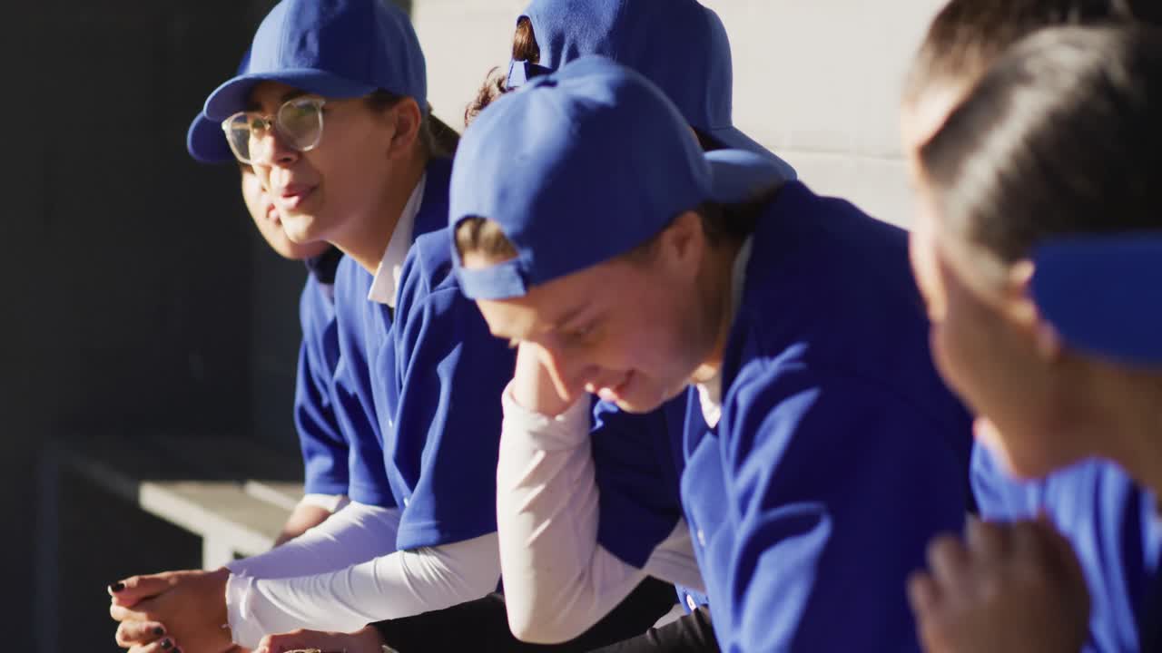 여자 야구 선수 들 의 다양한 그룹 이 벤치 에 앉아 코치 를 듣고 있다