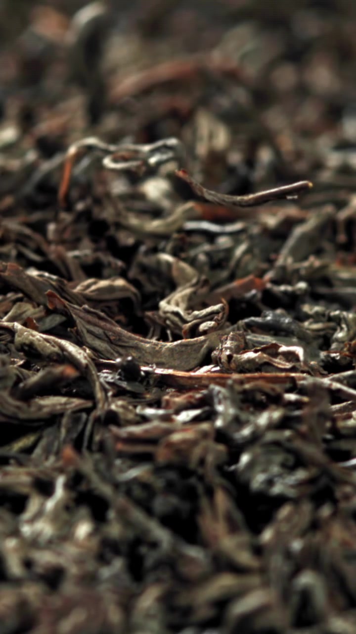 Loose Leaf Tea Falling onto a Pile of Dried Tea Leaves