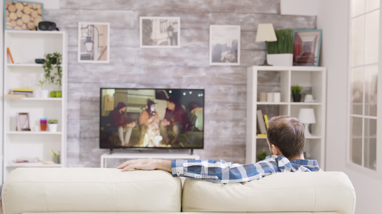 Uomo che guarda la TV in salotto