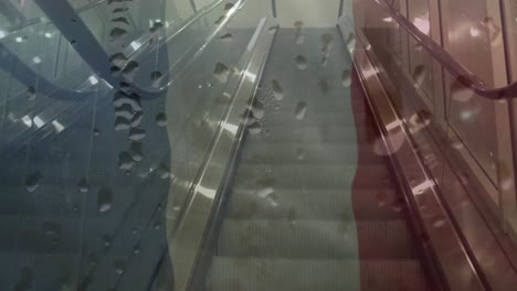 Animation-of-flag-of-france-with-water-drops-over-escalator-in-modern-building