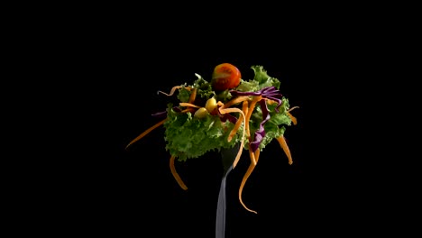 vegetables salad food on fork on black background.