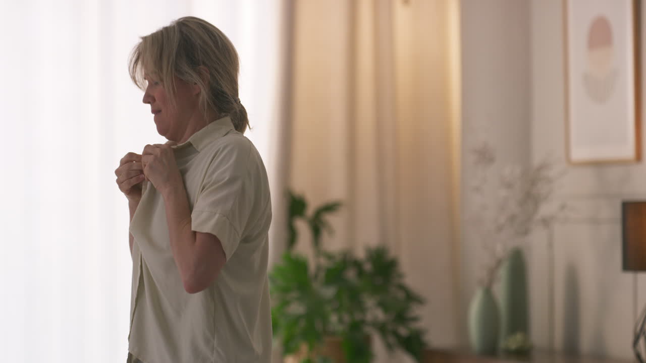 Woman Buttoning Shirt Indoors